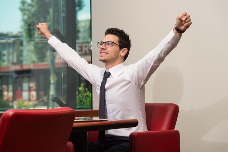 Successful Business Man With Arms Up At The Office
